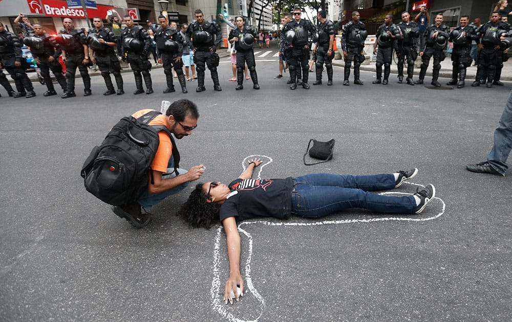 A woman lays on the ground pretending to be a dead body in front of Brazil`s police during a protest against the money spent on the WCup 2014 and demanding better public services, in Rio de Janeiro, Brazil.