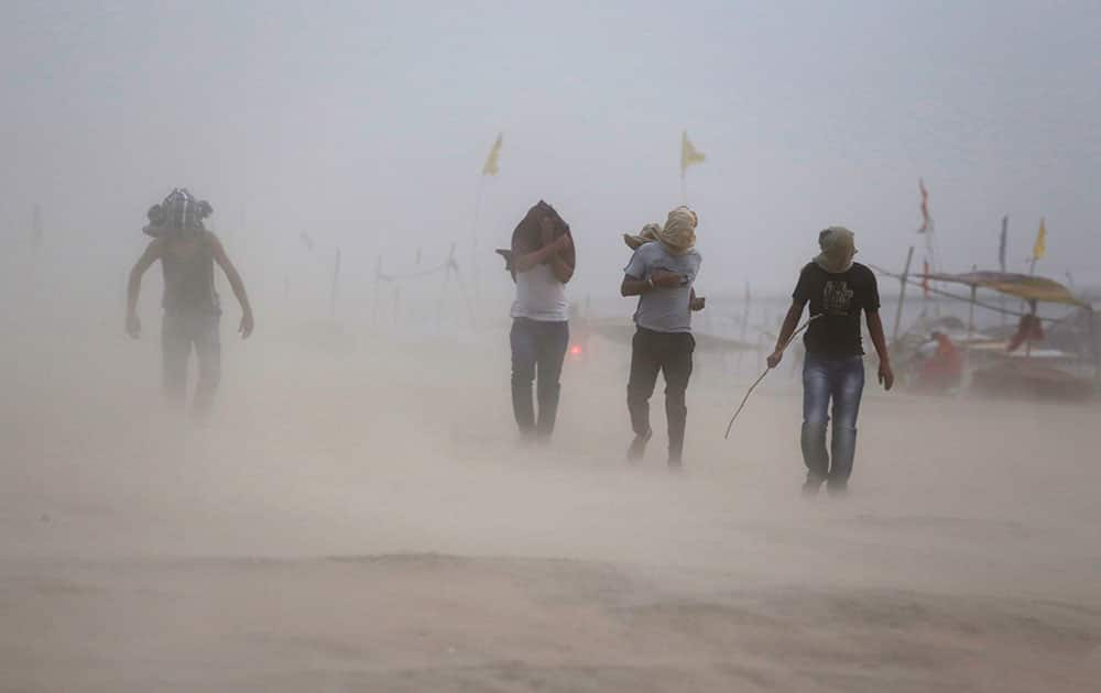 Indians walk during a dust storm on the banks of Sangam, the confluence of rivers the Ganges and the Yamuna in Allahabad.