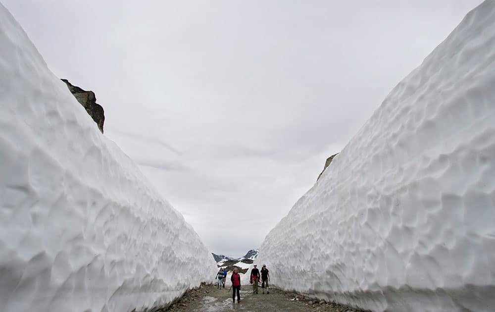 Hikers make their way past snow walls reaching as high as twenty feet along a hiking trail on Whistler mountain in Whistler, B.C.