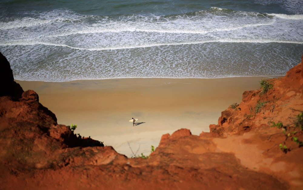 A surfer carries his board along the shoreof the Cacimbinha beach in Tibau do Sul, near Natal, Brazil.