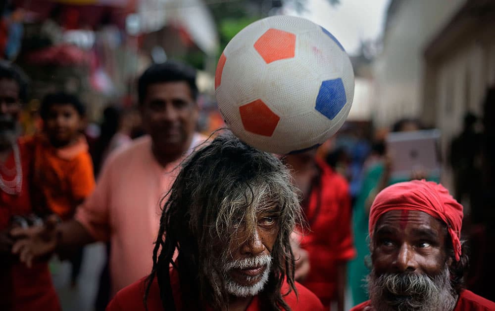 A Sadhu, or Hindu holy man, balances a ball on his head as others watch at the Kamakhya temple in Gauhati, India.