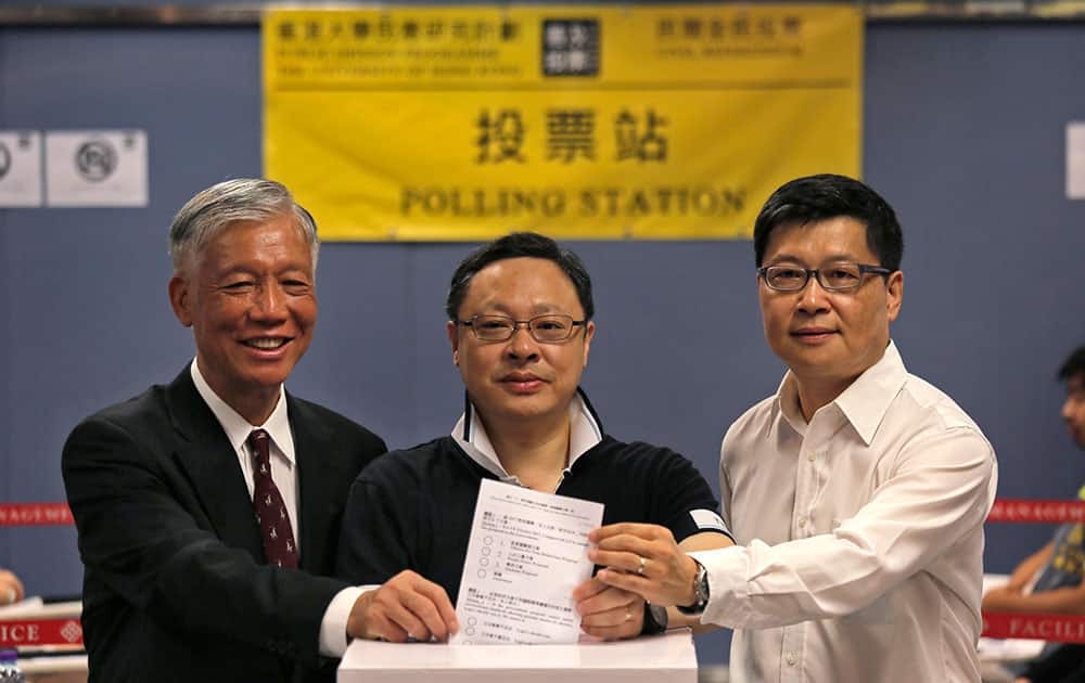 From right to left, Occupy Central co-organizer Chan Kin-man, Benny Tai and Chu Yiu-ming, pose at a polling center with a ballot for an unofficial referendum in Hong Kong.