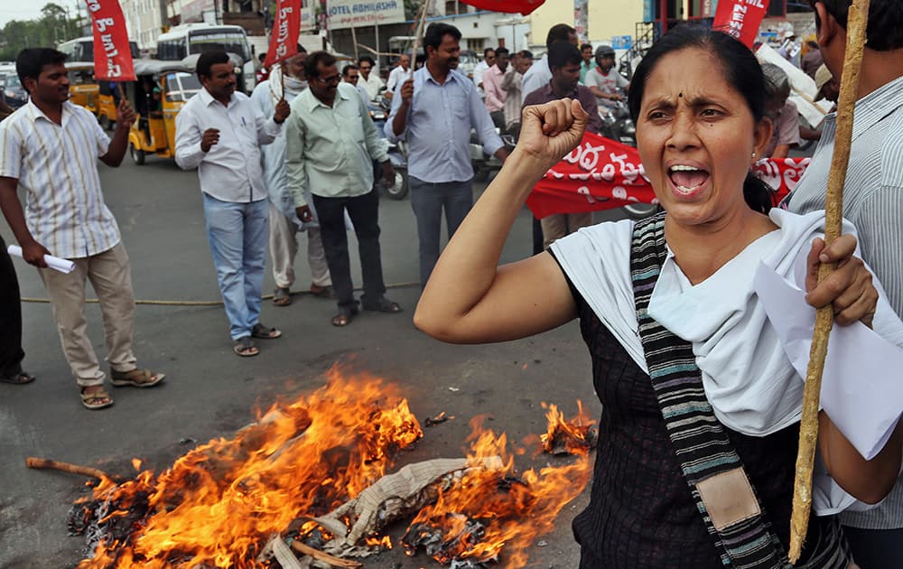 An Indian activist of Progressive Democratic Students Union (PDSU) shouts slogans as others burn an effigy of the ruling National Democratic Alliance (NDA) during a protest against hike in rail fares in Hyderabad.