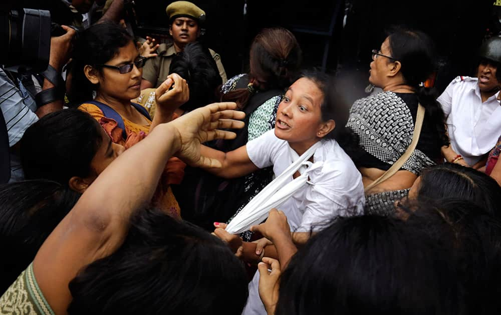 An Indian policewoman, center, is surrounded by activists of Socialist Unity Center of India (SUCI) during a protest against hike in rail fare, outside the Governor`s house in Kolkata