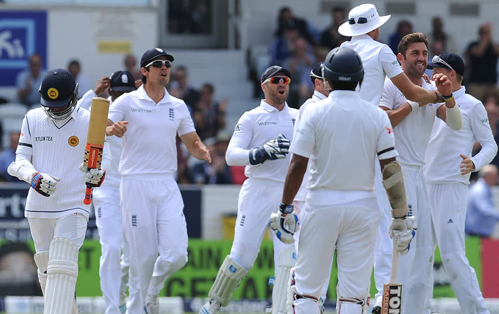 England team members celebrate as Sri Lanka`s Dimuth Karunaratne, left, walks after being bowled by England`s Liam Plunkett for 28 runs during their Second Test Match at Headingley cricket ground, Leeds, England.