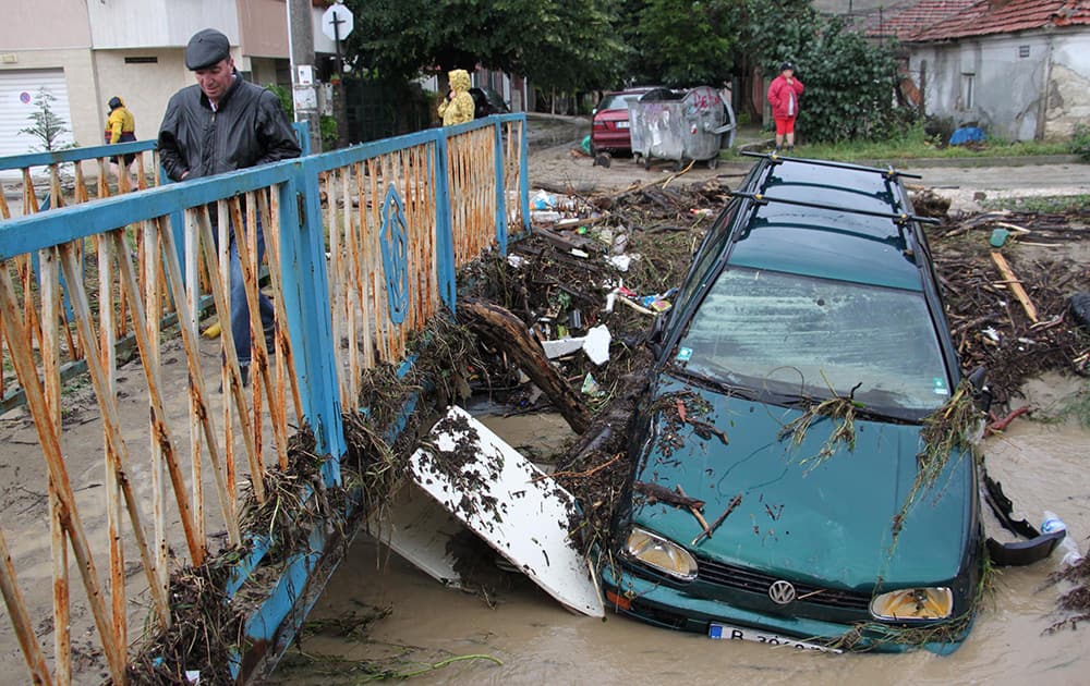 A man walks past debris and cars swept away by severe flooding in the town of Varna, Bulgaria.