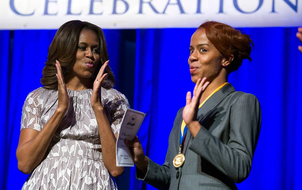 First lady Michelle Obama and graduate Jamila Lee mimic dancing as Lee is presented with a Student Achievement Award following Obama`s address at the DC College Access Program Class of 2014 graduation in Washington.