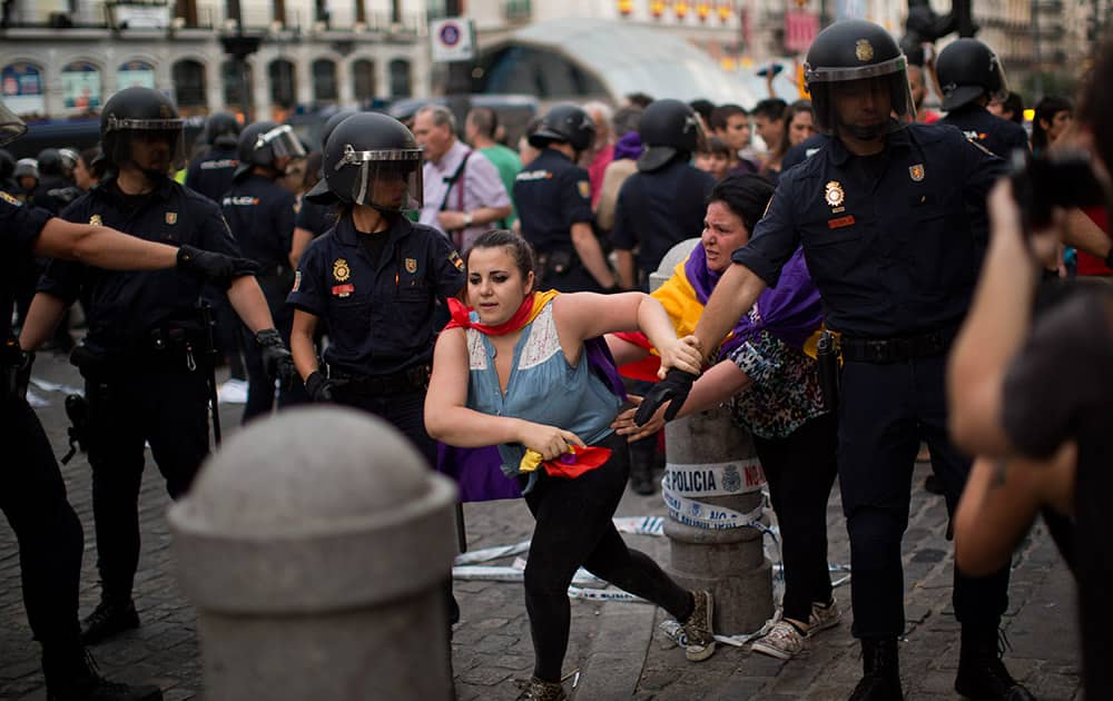 A Republican demonstrator runs away from riot police officers during a protest against the monarchy in the center of Madrid, Spain.