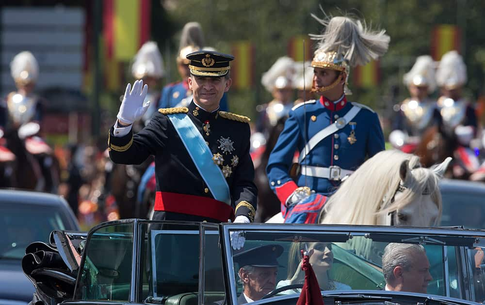 Spain’s newly crowned King Felipe VI waves next to Queen Letizia from an open-top Rolls Royce in the streets in Madrid