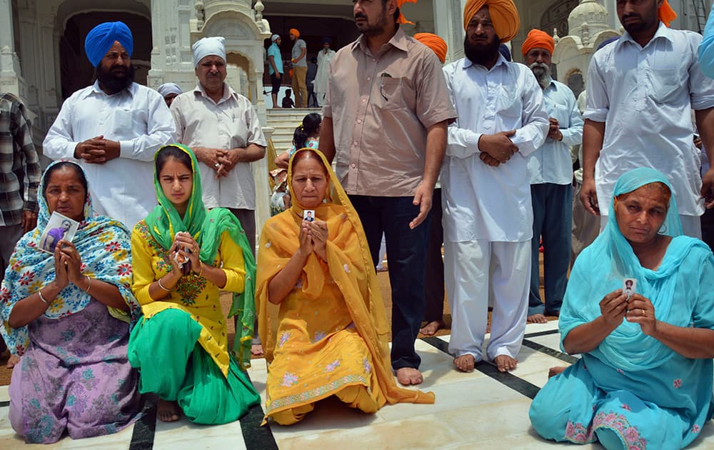 Family members pray for the safety of their missing sons as they display their photographs during their visit to the Golden Temple, Sikh’s holiest temple, in Amritsar.