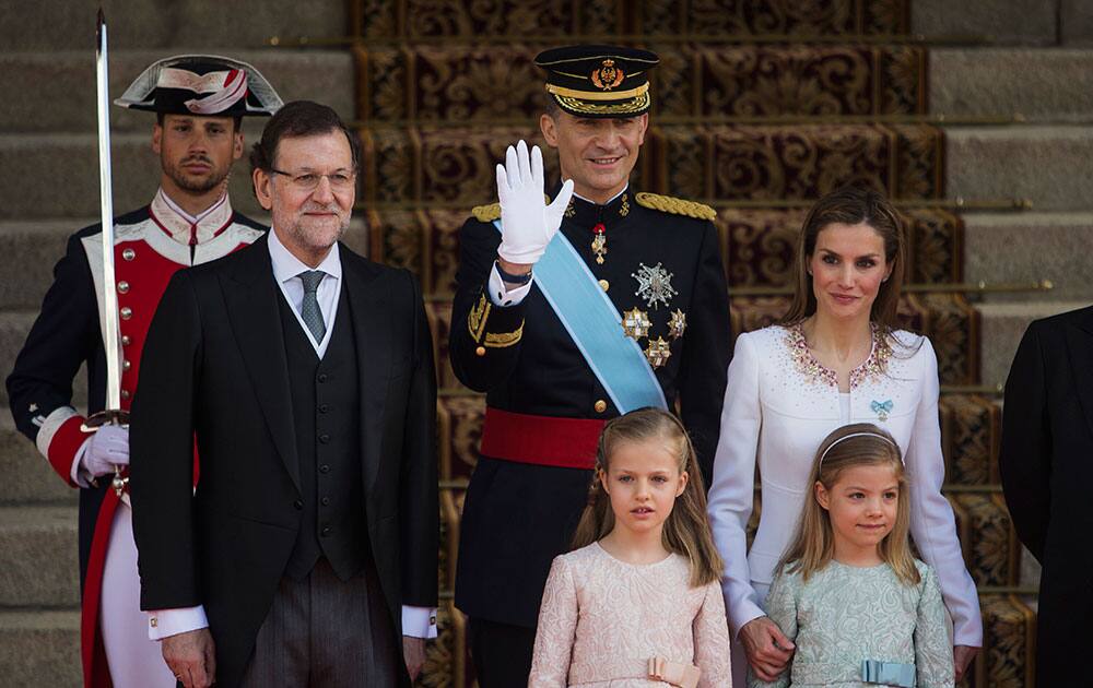 Spain’s newly crowned King Felipe VI, top center, accompanied by Spanish Prime Minister Mariano Rajoy, top second left, Spanish Queen Letizia, top right, Princess Sofia, bottom right, and Princess Leonor, waves as they arrive at the Parliament in Madrid, Spain. King Felipe VI has taken part in the first official act of his reign, receiving the red sash of Captain General of the Armed Forces from his father Juan Carlos.