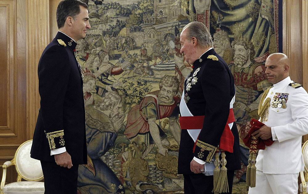 Spain`s King Juan Carlos, center, stands before handing over his military chief sash to Spain`s newly crowned King Felipe VI, left, during a ceremony at the Zarzuela Palace in Madrid, Spain.