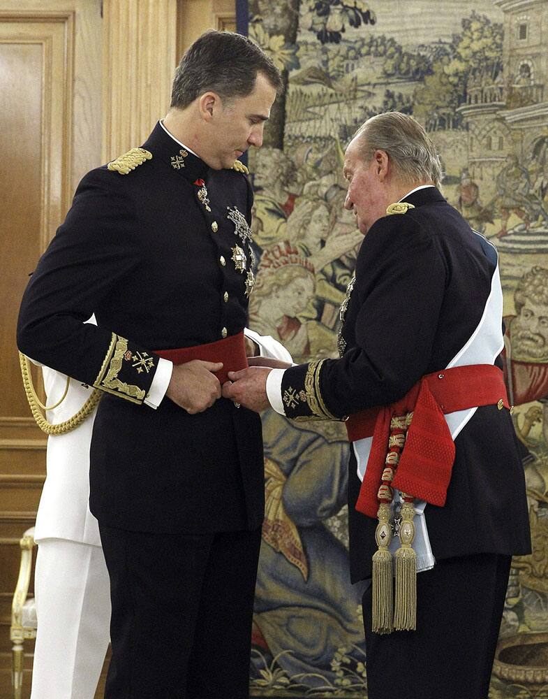 Spain`s King Juan Carlos, right, hands over his military chief sash to Spain`s newly crowned King Felipe VI during a ceremony at the Zarzuela Palace in Madrid, Spain.