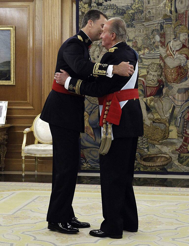 Spain`s King Juan Carlos, right, hugs his son Spain`s newly crowned King Felipe VI after handing over his military chief sash to him during a ceremony at the Zarzuela Palace in Madrid, Spain.