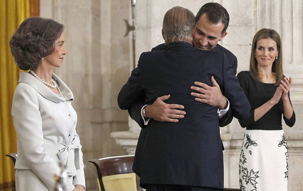 Spain`s Crown Prince Felipe, centre right , embraces his father, Spain’s King Juan Carlos in the presence of Queen Sofia, left and Princess Letizia after he signed an abdication law during a ceremony at the Royal Palace in Madrid, Spain.