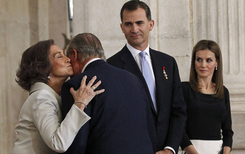 Spain’s King Juan Carlos, 2nd left is kissed by Queen Sofia, left in the presence of Spain`s Crown Prince Felipe, 3rd left and Princess Letizia after he signed an abdication law during a ceremony at the Royal Palace in Madrid, Spain.