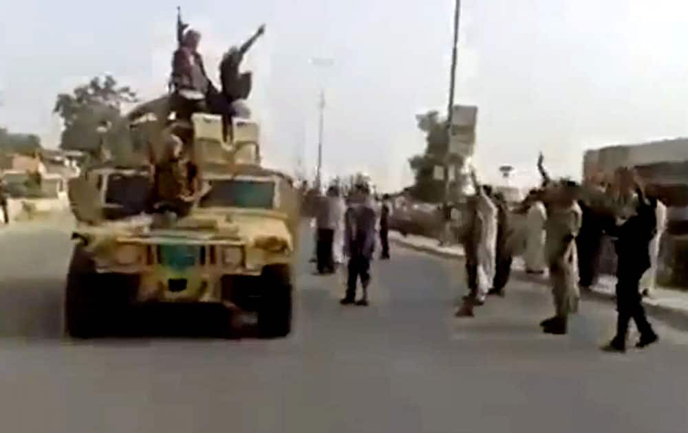 In this Tuesday, June 17, 2014 image taken from video uploaded to a militant social media account, which has been authenticated based on its contents and other AP reporting, al-Qaida-inspired Islamic State of Iraq and the Levant militants raise their weapons as they arrive to the country’s largest oil refinery in Beiji, some 250 kilometers (155 miles) north of the capital, Baghdad, Iraq. 