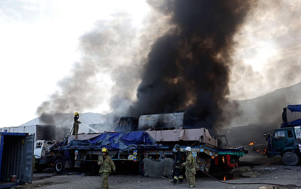 Firefighters work near the scene of an attack in Torkham, Nangarhar province, Afghanistan. Afghan officials say three Taliban suicide bombers targeted NATO fuel trucks at the border with Pakistan, setting off a gunbattle with police guards