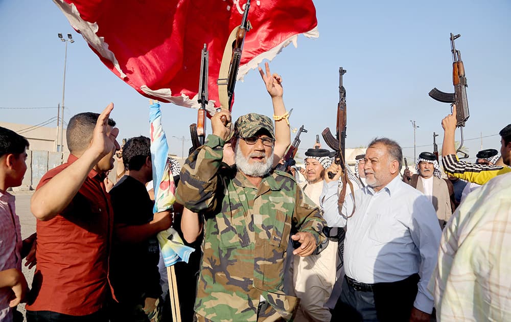 Iraqi Shiite tribal fighters raise their weapons and chant slogans against the al-Qaida-inspired Islamic State of Iraq and the Levant, after authorities urged Iraqis to help battle insurgents, in Baghdad`s Sadr city, Iraq. 