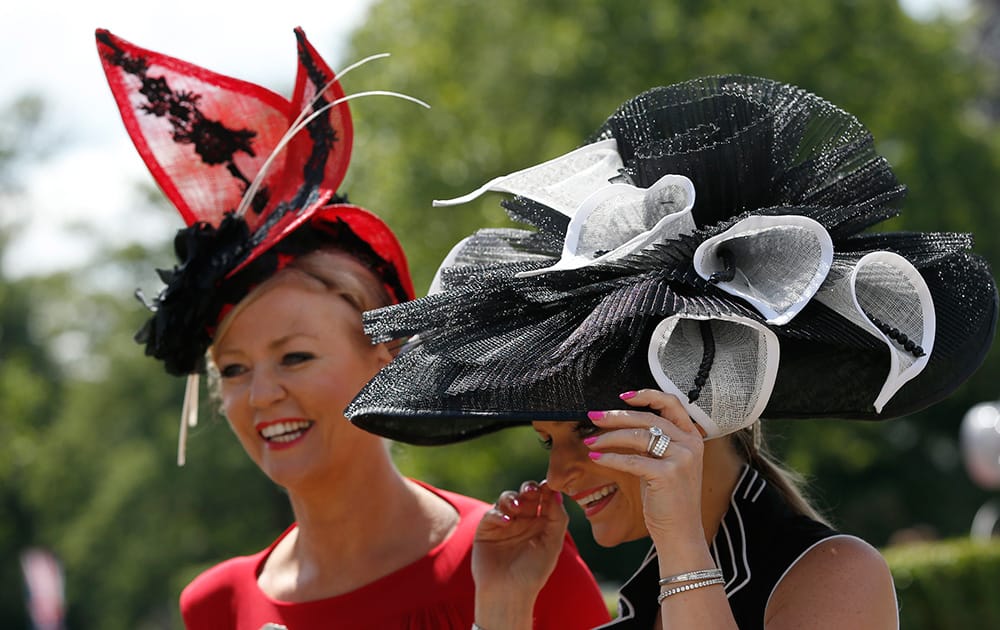 Race goers hang onto their hats in a gusty wind as they arrive on the first day of the Royal Ascot horse racing meeting at Ascot, England.