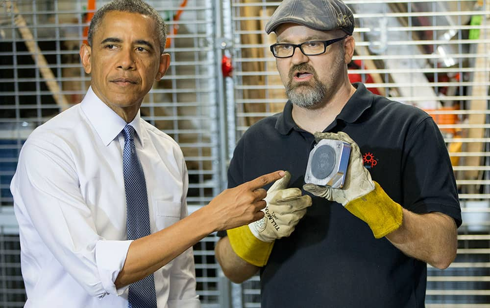 President Barack Obama points to a replica of the Presidential seal that Terry Sandin made during a tour of TechShop, in Pittsburgh, Pa. 