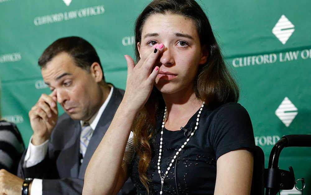 Injured circus acrobat Julissa Segrera, of the U.S., right, wipes away a tear while speaking with reporters as attorney Michael Krzak, left, wipes his eye during a news conference at Spaulding Rehabilitation Hospital.