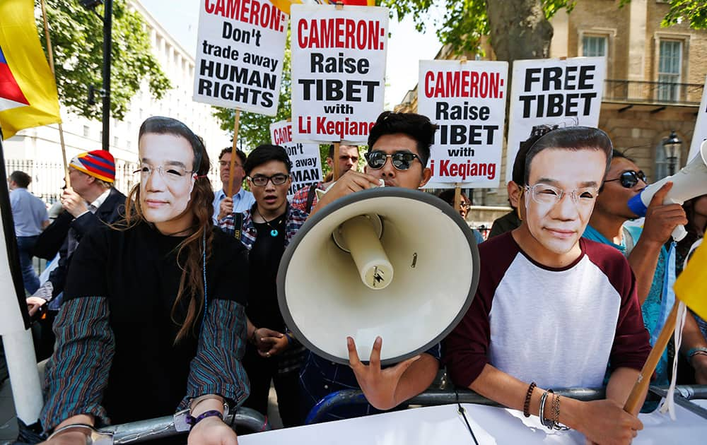 Tibetan demonstrators, some wearing masks depicting Chinese Prime Minister Li Keqiang and wearing handcuffs, participate in a protest against his visit, across the street from Downing Street in central London, where he was meeting with British Prime Minister David Cameron at his official residence.