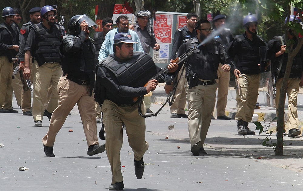 A Pakistani police officer fires his rifle in the air to disperse protestors during clashes in Lahore, Pakistan. Police clashed Tuesday with followers of an anti-Taliban cleric critical of Pakistan`s government in the eastern city of Lahore, violence that killed at least five people, officials said.