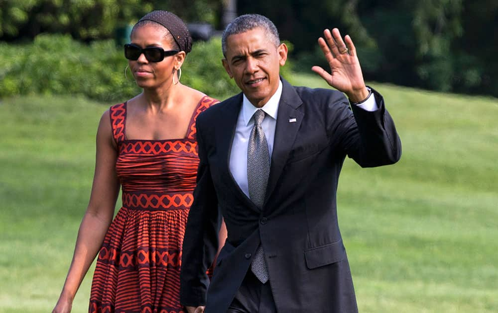 President Barack Obama waves as he walks with first lady Michelle Obama on their return to the White House from a trip to California, in Washington. 