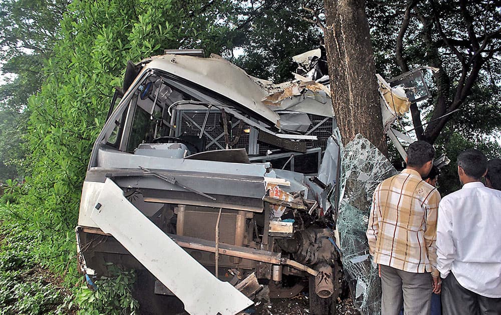 People looking at the damaged bus that hit a roadside tree at village Koparde in Kolhapur.
