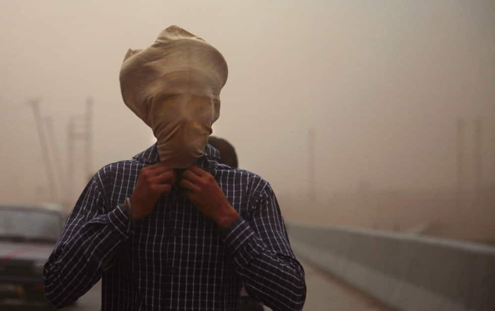 An Indian commuter covers his face with a cloth during a powerful dust storm in Jammu, India.