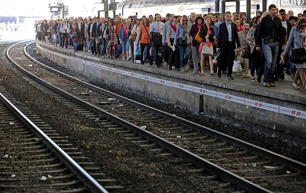 Commuters arrive at the Saint Lazare station with one of the few trains available today, in Paris. French rail workers are on strike to protest a reorganization of the national rail and train companies.