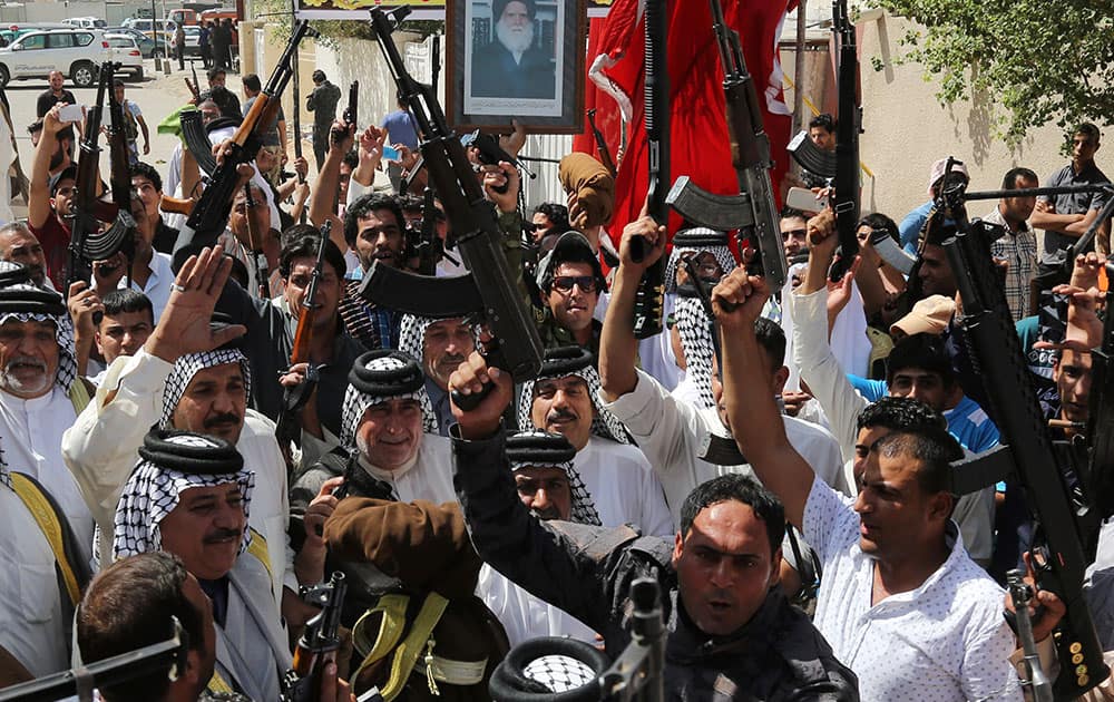 Iraqi Shiite tribal fighters raise their weapons and chant slogans against the al-Qaida-inspired Islamic State of Iraq and the Levant (ISIL) in Baghdad`s Sadr city, Iraq.