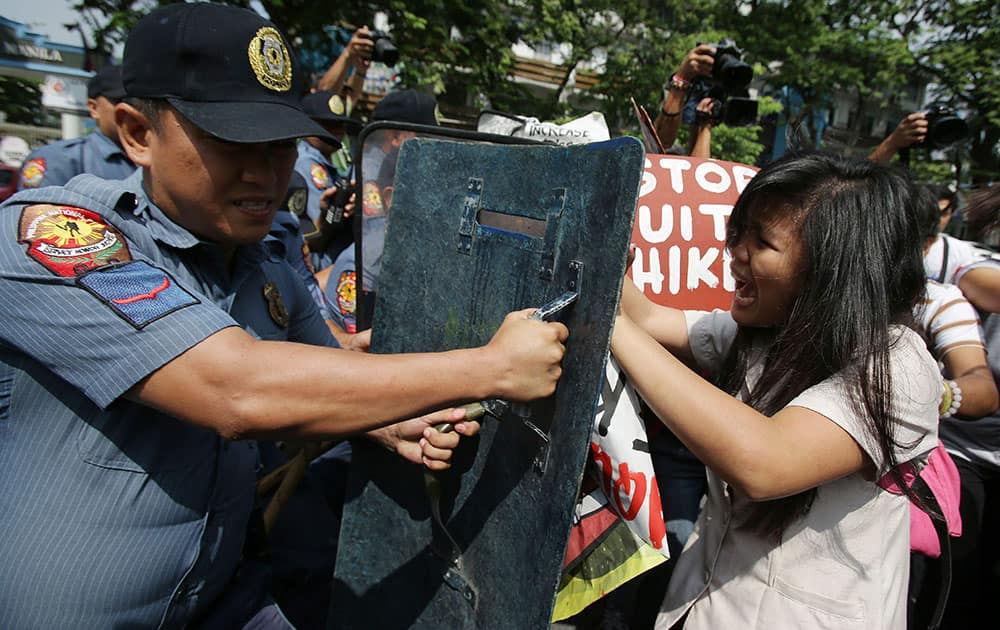 A Filipino student reacts as a policeman uses his shield to push she and other protesters back while they try to get near the gates of the Malacanang presidential palace in Manila, Philippine.