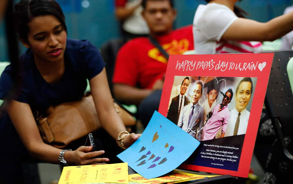 A relative of one of Malaysian passengers on board the missing Malaysia Airlines Flight 370 looks at a picture of missing crew during an event to commemorate the 100th day after the flight went missing, in Kuala Lumpur.