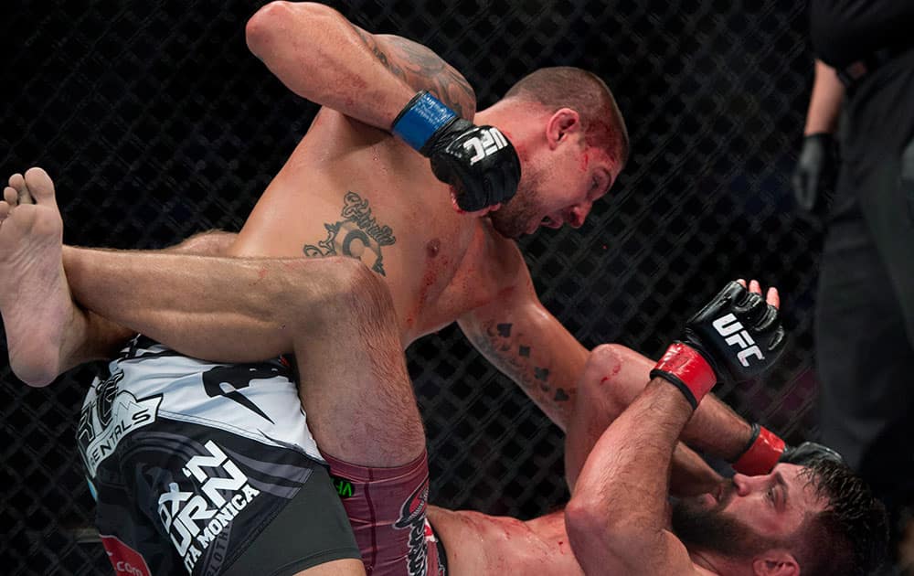 Andrei Arlovski, bottom, takes a punch from Brendan Schaub, of the United States, during a heavyweight bout at UFC 174 in Vancouver, British Columbia.