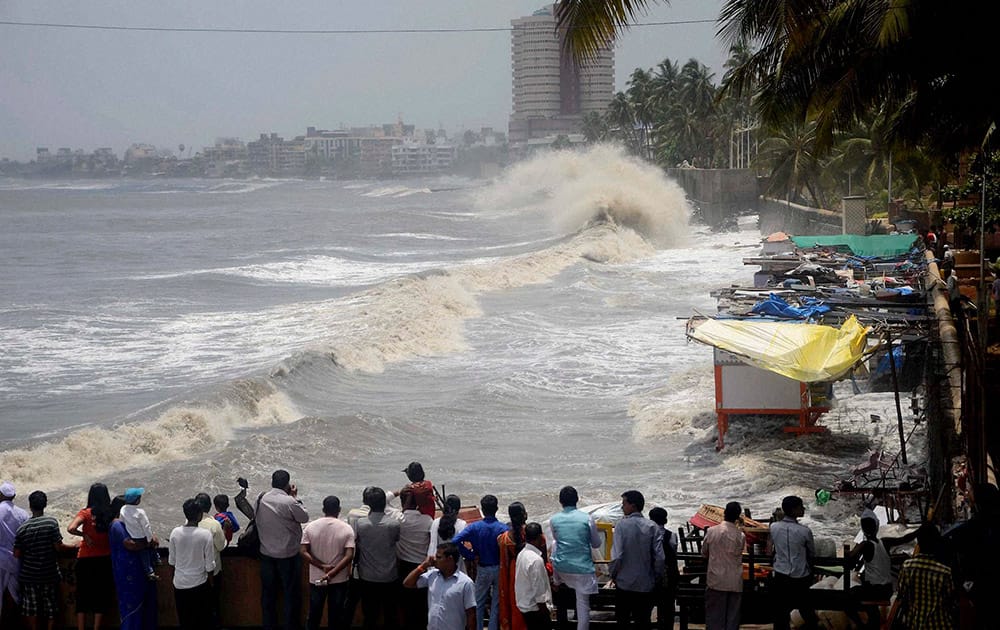 People look on as a high tide strikes Dadar seaface in Mumbai.