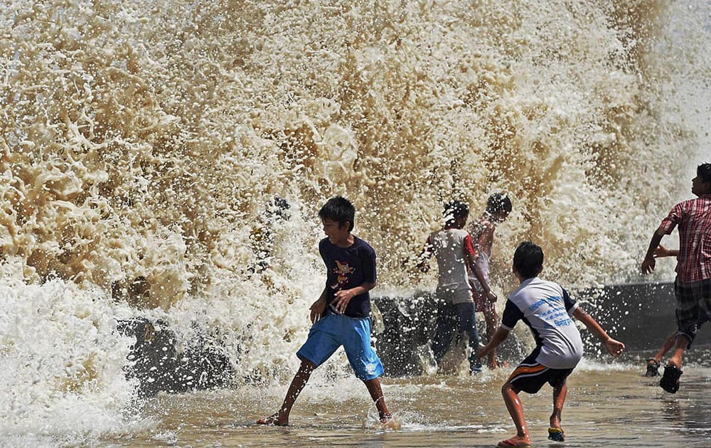 Children enjoy a high tide at Worli seaface in Mumbai.