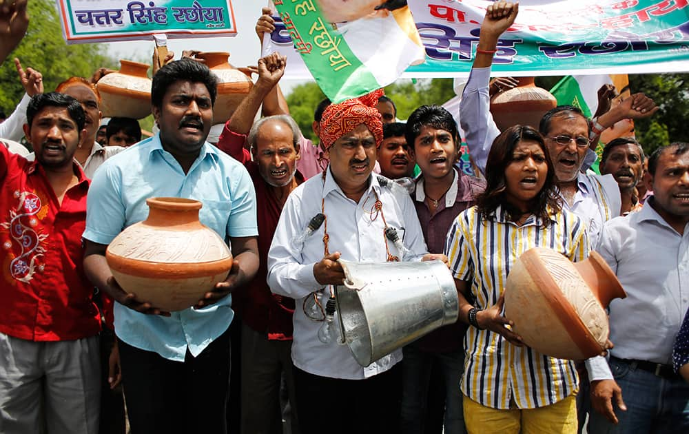 Supporters of Congress party shout slogans as they carry a bucket and earthen pots outside the ruling Bharatiya Janata Party (BJP) office during a protest against long power cuts and water shortage in New Delhi.