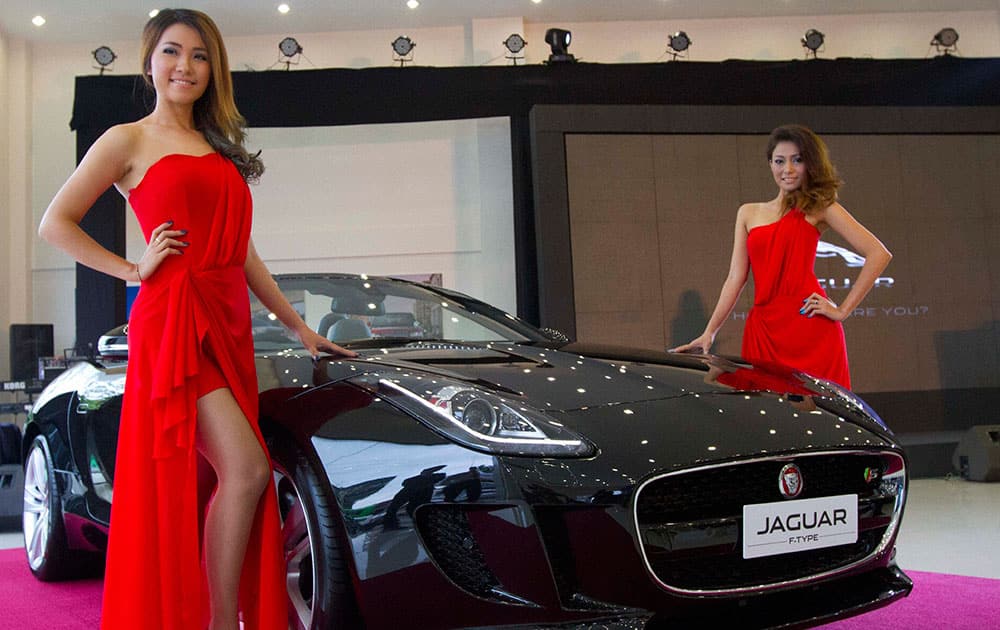 Myanmar models pose for photos by a Jaguar model during a launch ceremony of Jaguar Land Rover Motor Company Showroom in Yangon, Myanmar.