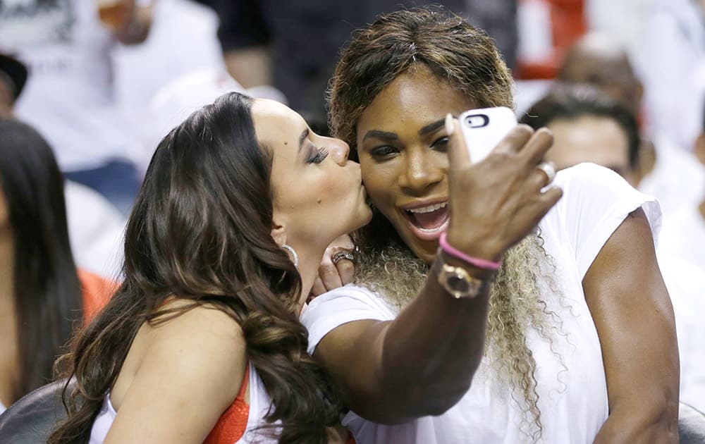 Adrienne Bosh, wife of Miami Heat player Chris Bosh, kisses tennis player Serena Williams as Willians takes a photo during the first half Game 6 in the NBA basketball playoffs Eastern Conference finals between the Indiana Pacers and the Heat, in Miami.