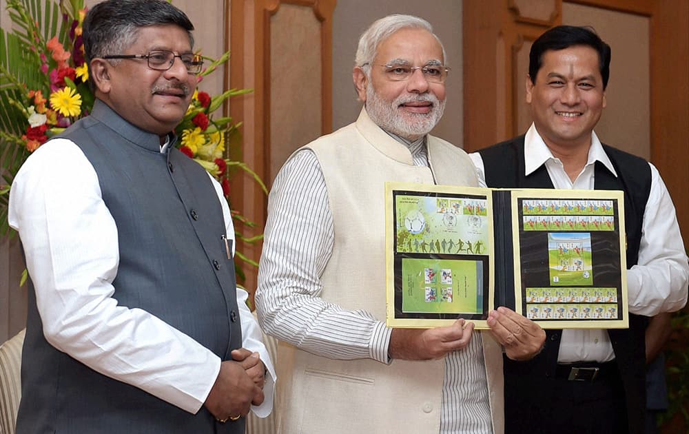 Prime Minister Narendra Modi with Communication and IT Minister Ravi Shanker Prasad and Sports Minister Sarbananda Sonowal releases commemorative postage stamps on the 2014 FIFA World Cup, in New Delhi.