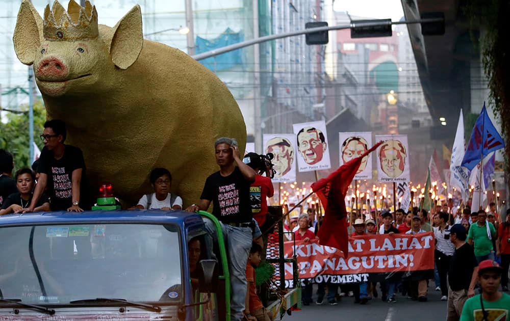 A giant effigy of a pig, leads activists carrying lighted torches, as they march towards the Presidential Palace in Manila to demand that Philippine President Benigno Aquino III prosecute all officials, including some of his allies, who were allegedly involved in stealing from state funds, known as pork barrel funds, which are intended for projects to help the poor in the Philippines.