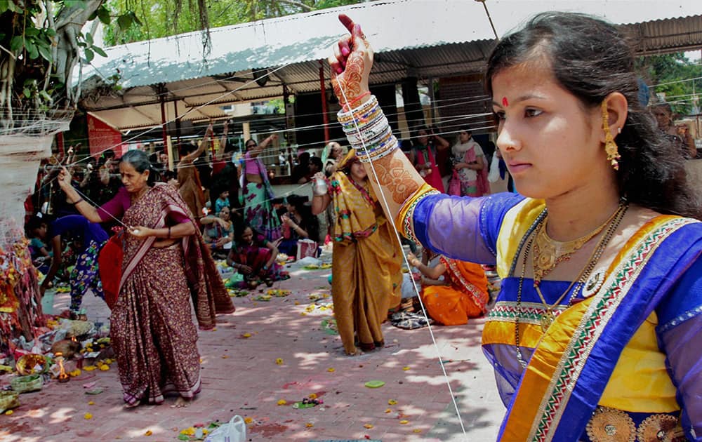 Married women tie threads around a Banyan trees on `Vat Savitri` festival at a temple in Ahmedabad.