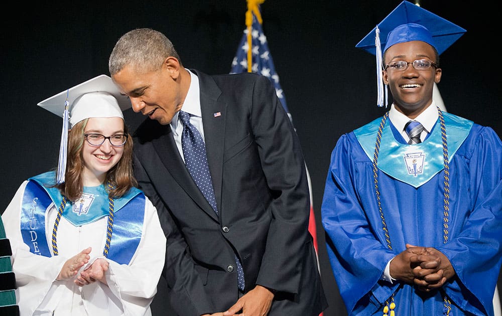 President Barack Obama leans over to talk to class Valedictorian Naomi Desilets, left, prior to delivering the commencement address at Worcester Technical High School, in Worcester, Mass. At right is Student Body President Reginald Sarpong. 