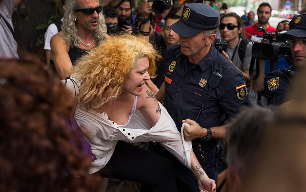 A riot police officer grabs a protestor who was shouting slogans against the monarchy, during a protest against the Monarchy near the parliament in Madrid, Spain.