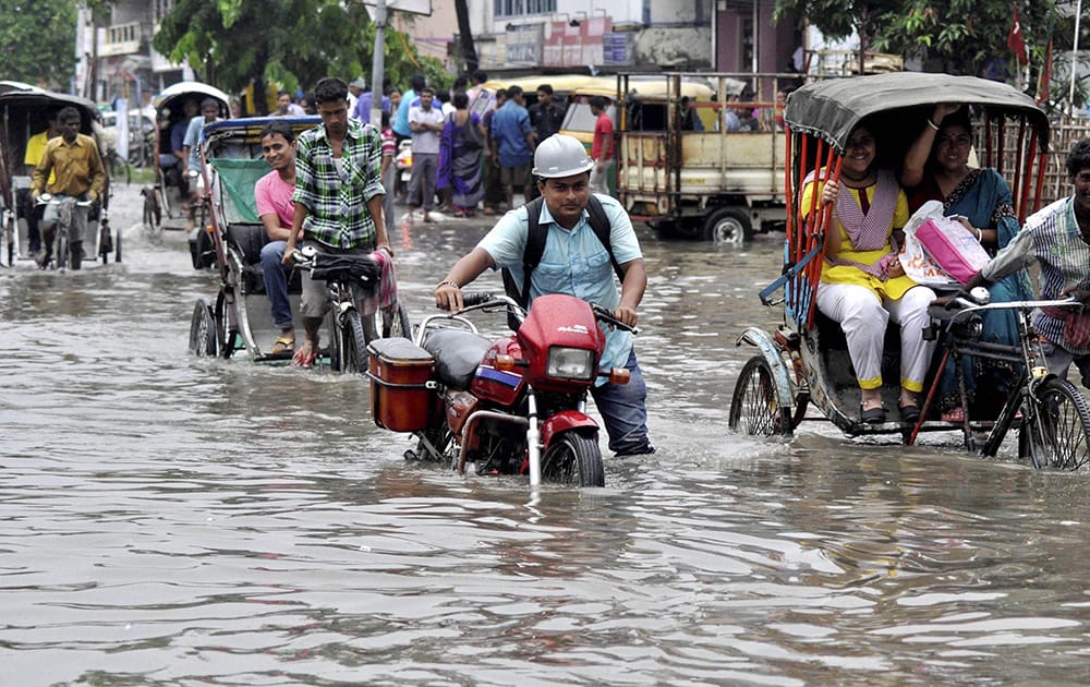 People wade through a waterlogged street after heavy rains in Agartala.