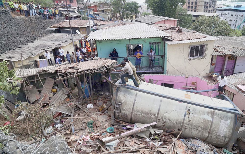 People salvage a shanty after a tanker fell off the Mumbra bypass on the slum houses in Thane, Mumbai.