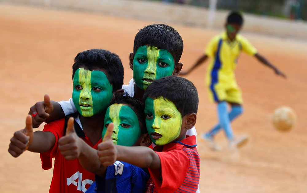 Indian boys with faces painted in colors resembling those of the Brazil`s flag pose for photographers, during a game of soccer in Bangalore.