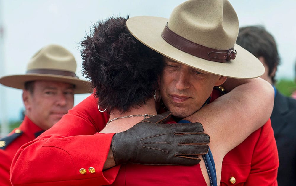 An officer is embraced at the end of the regimental funeral for the three Royal Canadian Mounted Police officers, who were killed on duty, at the Moncton Coliseum in Moncton, New Brunswick.